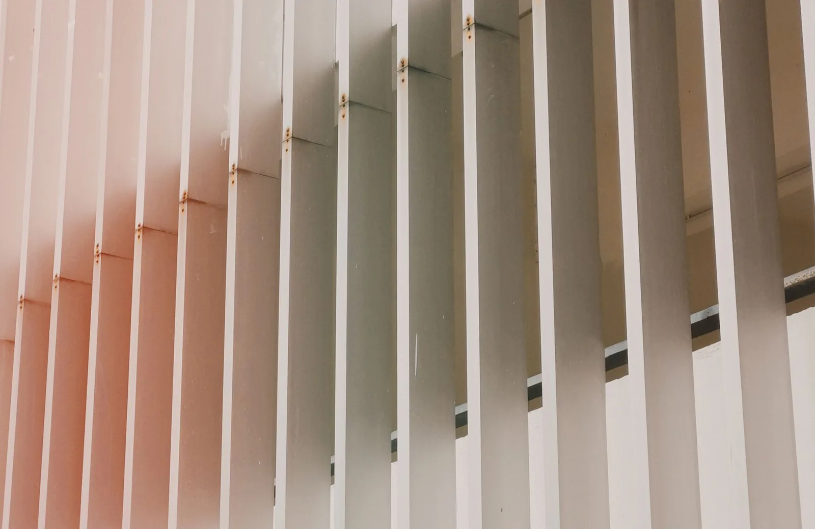 Linear aluminium fins casting fine shadows across a plaster wall