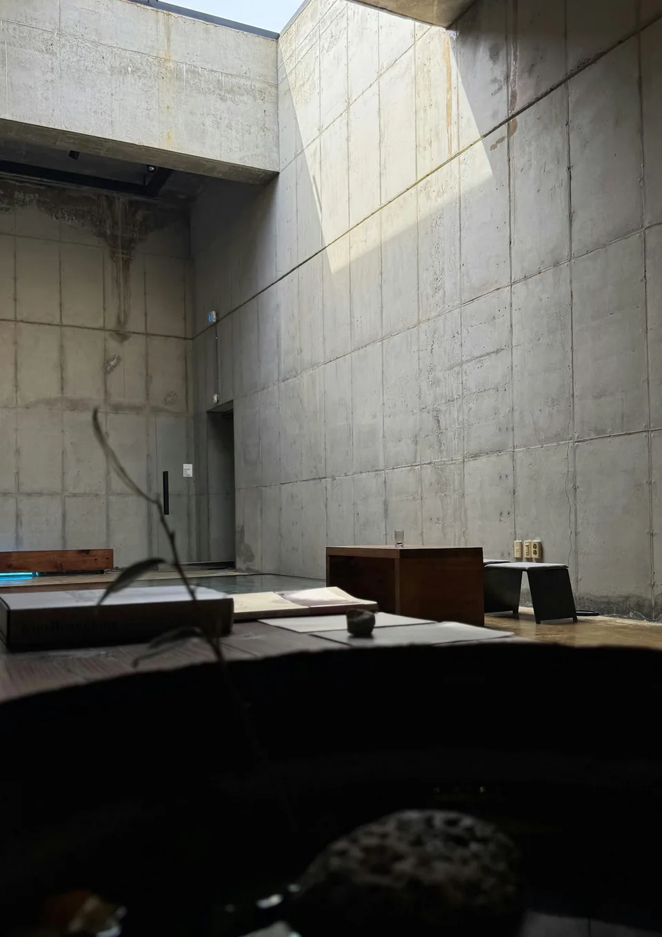 Sunlight falling into a concrete room with a still water feature