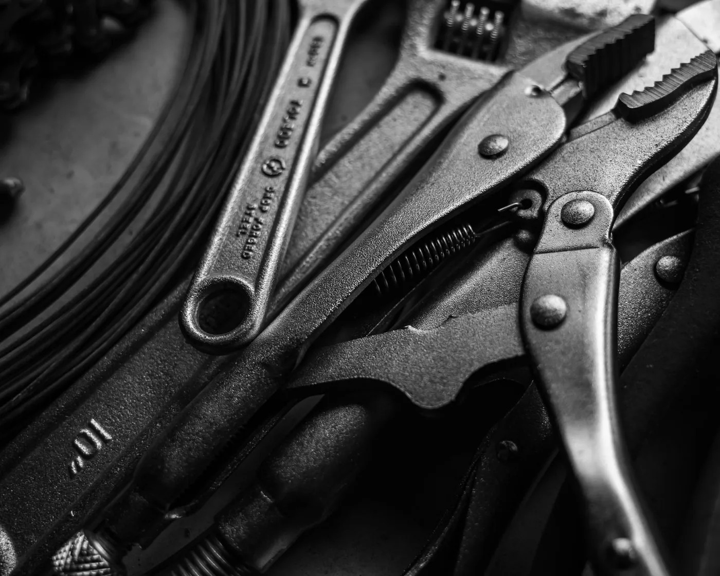 Wrenches and grips laid out on a workbench, monochrome